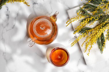 Glass Cup 'ta çay ve Mimosa şubesiyle Sunny Spring' de cam çaydanlık. Üst görünüm