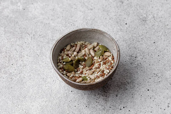 Çiğ, gri masadaki et suyu kabuğundaki farklı tohumları soydu. Sağlıklı beslenme, vejetaryen gıdalar salata ile yaratıcı konsept. Kabak çekirdeği, ayçekirdeği, susam çekirdeği.