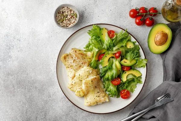Frillis salatası, domates, avokado ve tohumlu fırında beyaz balık. Sağlıklı balık, akşam yemeği. Üst görünüm