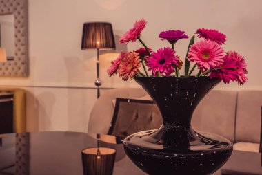 Lüks bir iç mekanda cam masada zarif bir buket mor gerbera.