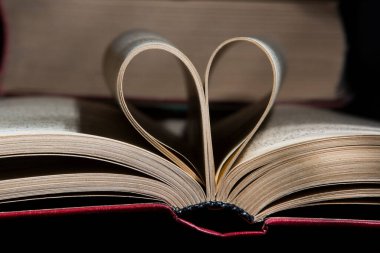 Ahşap bir arka planda kalp şeklinde açık bir kitap