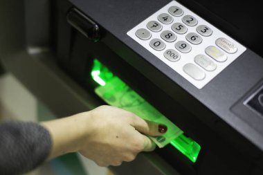 A female hand inserting a credit card into an ATM