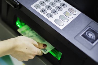 A female hand inserting a credit card into an ATM