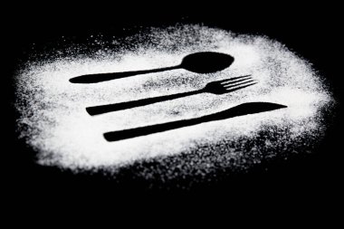 Siyah beyaz bir çatalın siyah arka planda kaşıkla çekilmiş fotoğrafı.