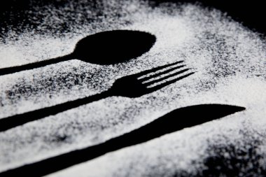 Siyah beyaz bir çatalın siyah arka planda kaşıkla çekilmiş fotoğrafı.