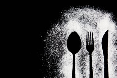 Siyah beyaz bir çatalın siyah arka planda kaşıkla çekilmiş fotoğrafı.