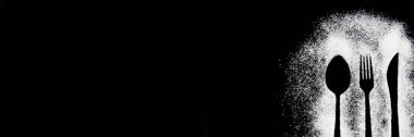 Siyah beyaz bir çatalın siyah arka planda kaşıkla çekilmiş fotoğrafı.