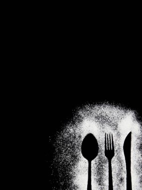 Siyah beyaz bir çatalın siyah arka planda kaşıkla çekilmiş fotoğrafı.