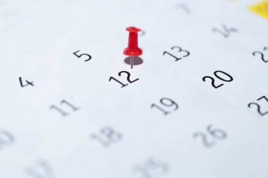 a close-up of a paper calendar on a blue background with text and a red pencil