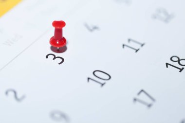 Beyaz arkaplanda iğne bulunan bir takvimin yakın plan görüntüsü