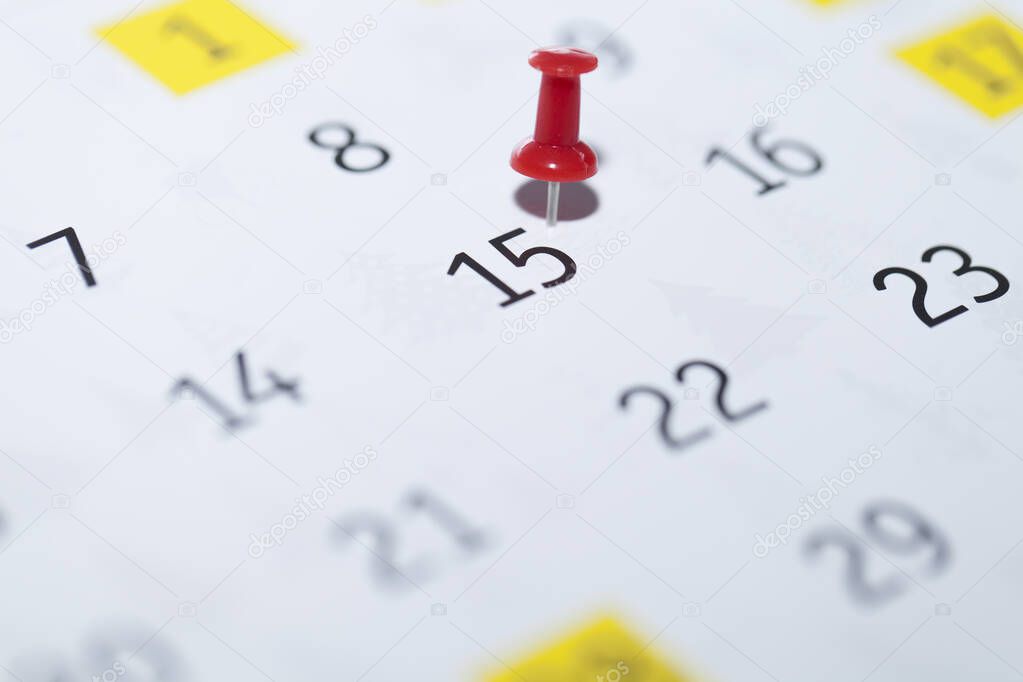 close up of a calendar with a pin on a white background