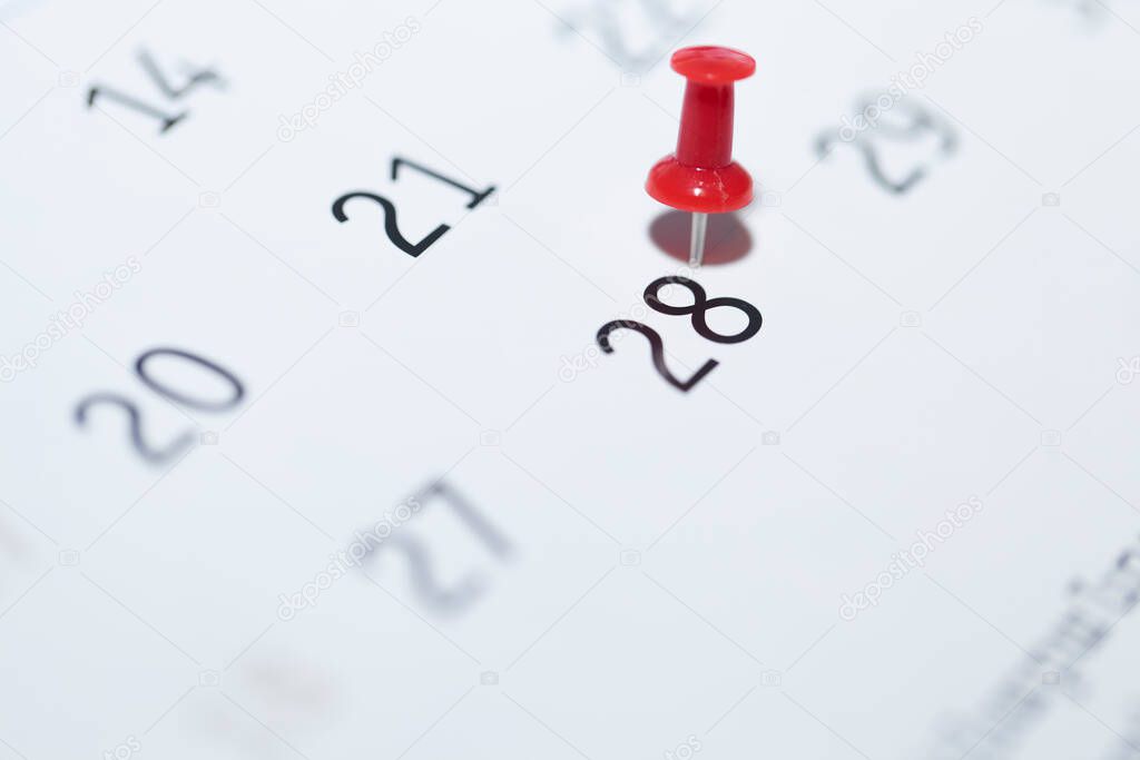 a closeup shot of a paper note with white pins and a calendar on a background