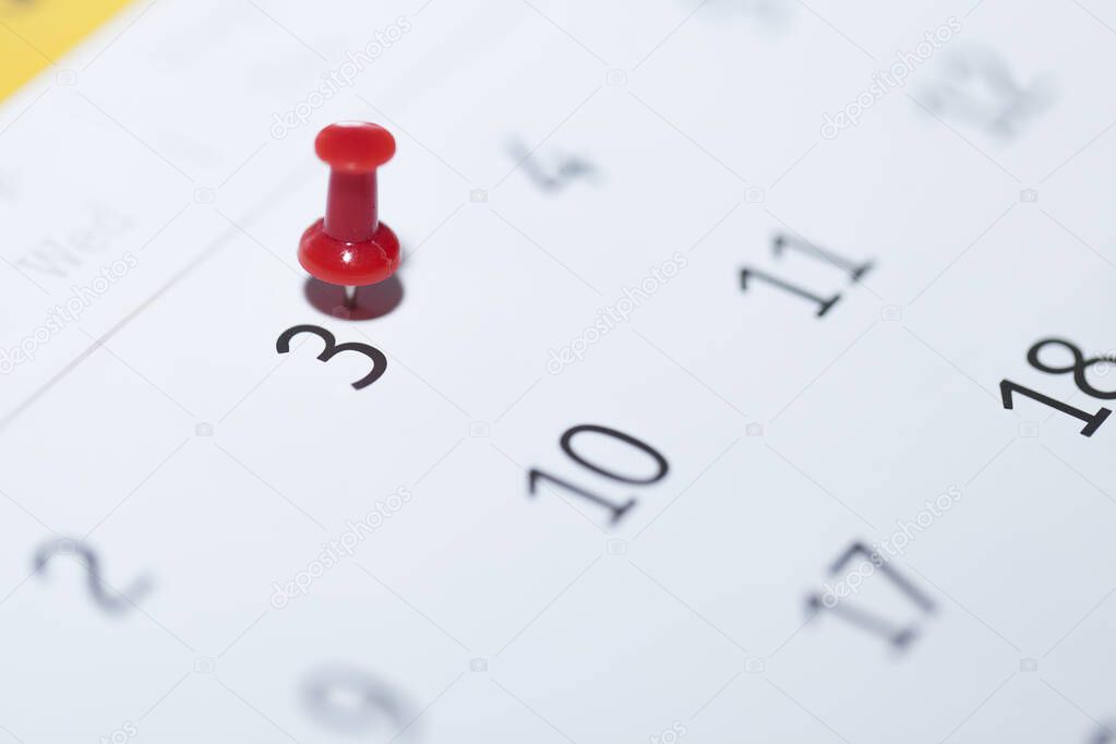 close-up of a calendar with a pin on a white background