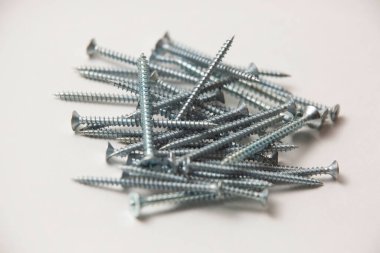 Gri plastik panel tıkaçlarının ve parlak metal vidaların izole edilmiş görüntülerini beyaz arkaplandaki yığının içinde kapat.