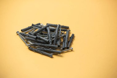 Gri plastik panel tıkaçlarının ve parlak metal vidaların izole edilmiş görüntüsünü kapat. Sarı arka planda..