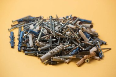 Gri plastik panel tıkaçlarının ve parlak metal vidaların izole edilmiş görüntüsünü kapat. Sarı arka planda..