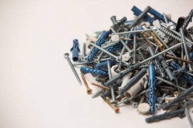 Gri plastik panel tıkaçlarının ve parlak metal vidaların izole edilmiş görüntülerini beyaz arkaplandaki yığının içinde kapat.