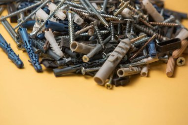 Gri plastik panel tıkaçlarının ve parlak metal vidaların izole edilmiş görüntüsünü kapat. Sarı arka planda..