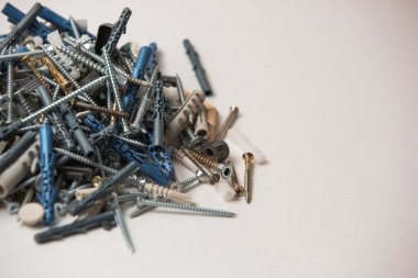 Gri plastik panel tıkaçlarının ve parlak metal vidaların izole edilmiş görüntülerini beyaz arkaplandaki yığının içinde kapat.