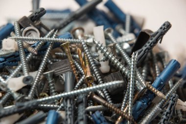 Gri plastik panel tıkaçlarının ve parlak metal vidaların izole edilmiş görüntülerini beyaz arkaplandaki yığının içinde kapat.