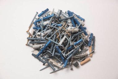 Gri plastik panel tıkaçlarının ve parlak metal vidaların izole edilmiş görüntülerini beyaz arkaplandaki yığının içinde kapat.