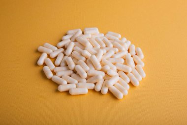 Turuncu arka planda beyaz ilaç kapsülleri