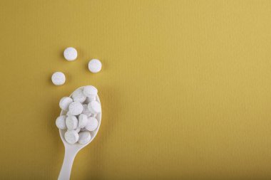 Sarı arka planda ilaçlı kaşık.