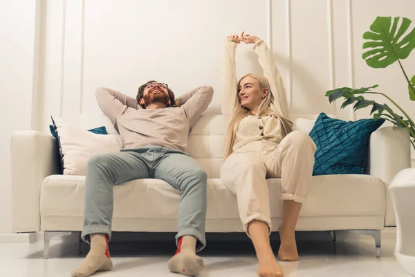 Gelukkig duizendjarig paar ontspannen samen op comfortabele bank in hun mooie heldere woonkamer — Stockfoto