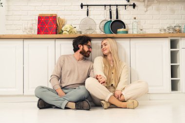 Orta yaşlı, beyaz sakallı bir adam mutfakta yerde güzel karısıyla oturuyor. Düşünüyor, kaynaşıyor. 