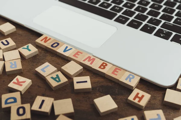 The name of the month November written on wooden cubes od the tabletop of th computer desk — Stock Photo, Image