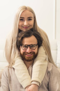 Mutlu Avrupalı Çift Kavramı. Milenyum sarışını uzun saçlı kadın önünde oturan esmer sakallı ortağının kafasına sarılıyor. Dikey Çekim.