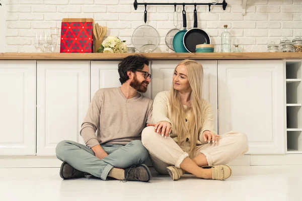 Lindo casal caucasiano na cozinha sentado no chão e intimamente falando uns com os outros, pensando sobre o seu futuro compartilhado — Fotografia de Stock