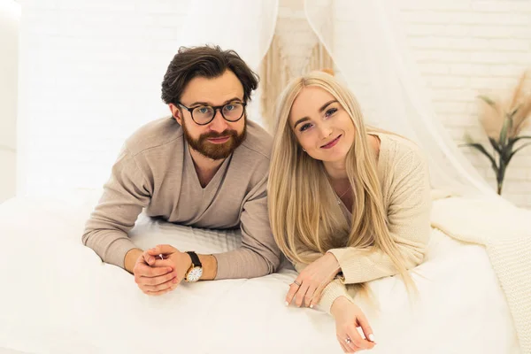 Молодий підприємець і його красива дівчина-бізнесмен лежить на ліжку, посміхаючись і дивлячись на камеру — стокове фото