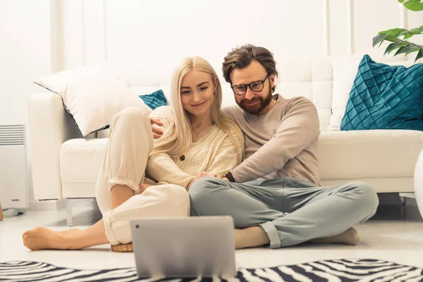 Blank blond langharige schoonheid zitten op de vloer met haar aanhankelijke partner en kijken naar video 's op hun laptop — Stockfoto