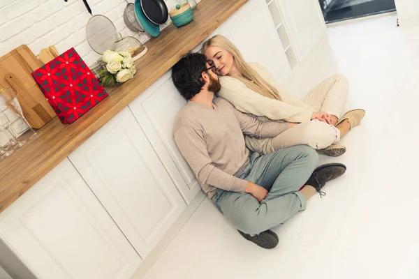 Twee Kaukasische mensen, mooie vrouw en haar middelbare leeftijd vriendje zitten op de vloer in de keuken, chatten, glimlachen, bonding — Stockfoto