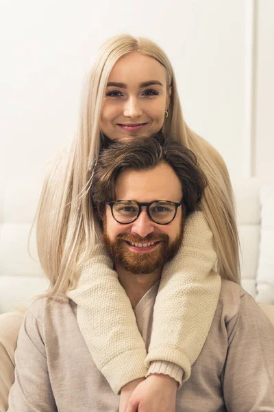 Vertical portrait of caucasian couple, blonde long-haired woman hugging her millennial bearded husband and smiling to the camera — Stock Photo, Image