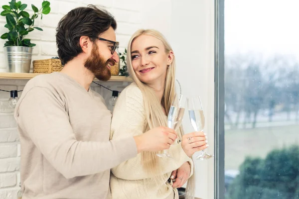Twee Kaukasische mensen vieren hun relatie en drinken champagne uit mooie glazen terwijl ze naast het raam staan — Stockfoto