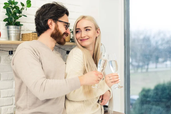 Jong paar glimlachen naar elkaar vieren hun verjaardag in de keuken door het drinken van champagne — Stockfoto