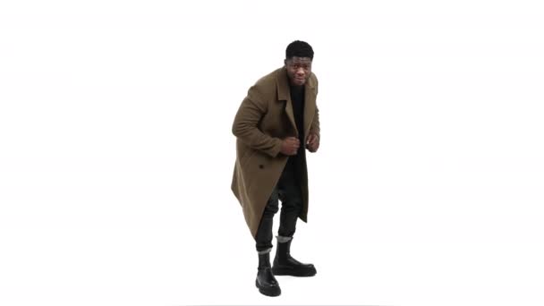 Komik siyah adam mankenlik yapıyor ve dans ediyor. Kahverengi ceket giyiyor. Beyaz arka plan. — Stok video
