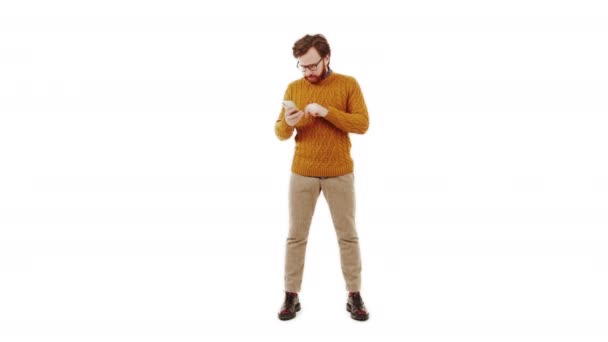 Medelålders brunett skäggig man tittar på sin telefon och gärna gester vit bakgrund isolerad studio skott — Stockvideo