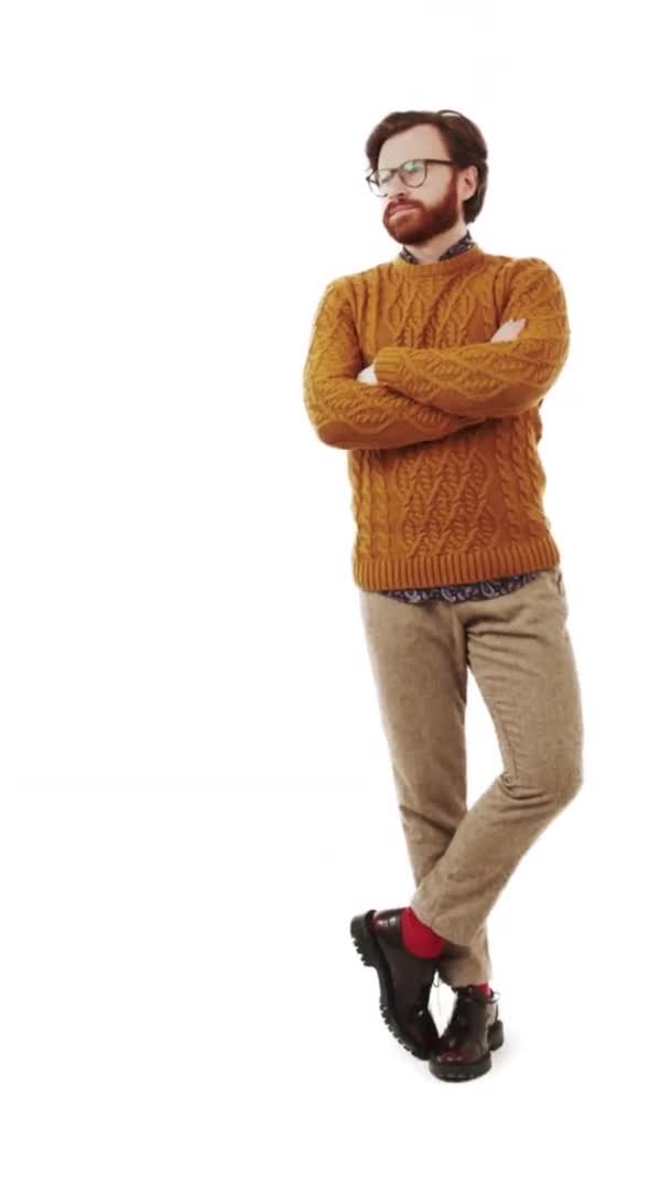 Ευρωπαίος γενειοφόρος που φοράει πορτοκαλί πουλόβερ με σταυρωμένα τα χέρια στο στήθος ενώ στέκεται σε λευκό φόντο στούντιο — Αρχείο Βίντεο
