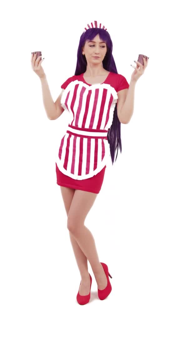 Jovem caucasiana vestindo avental listrado sobre mini vestido vermelho compartilhando bebida, esticando o braço Vertical Studio Shot — Vídeo de Stock