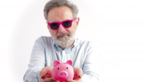 Homem de cabelos grisalhos em seus 40 anos segurando o banco rosa piggy investimentos e conceito de aposentadoria feliz — Vídeo de Stock