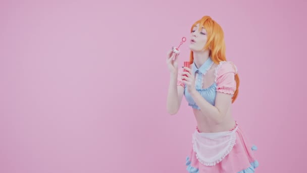 Studio Shot d'une jeune fille Kawaii qui souffle des bulles de savon fond rose — Video