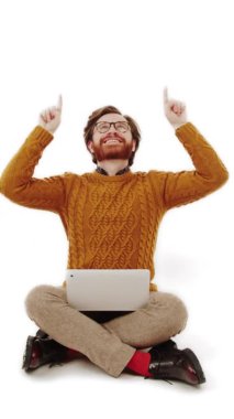 Turuncu kazaklı, dizlerinin üstünde dizlerinin üstüne çöküp fotokopi stüdyosunu gösteren turuncu sakallı adam beyaz arka plan.