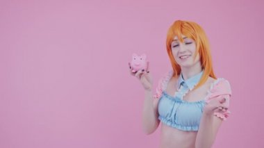 Tatlı Kafkas genç Cosplayer domuzcuk kumbarasını sallıyor ve daha çok parası var diye övünüyor.