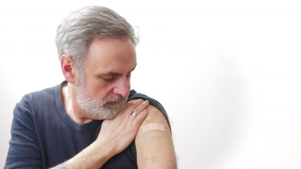 Kır saçlı, sakallı, yakışıklı bir adam, kovid 19 aşısından sonra kolunu gösteriyor. — Stok video