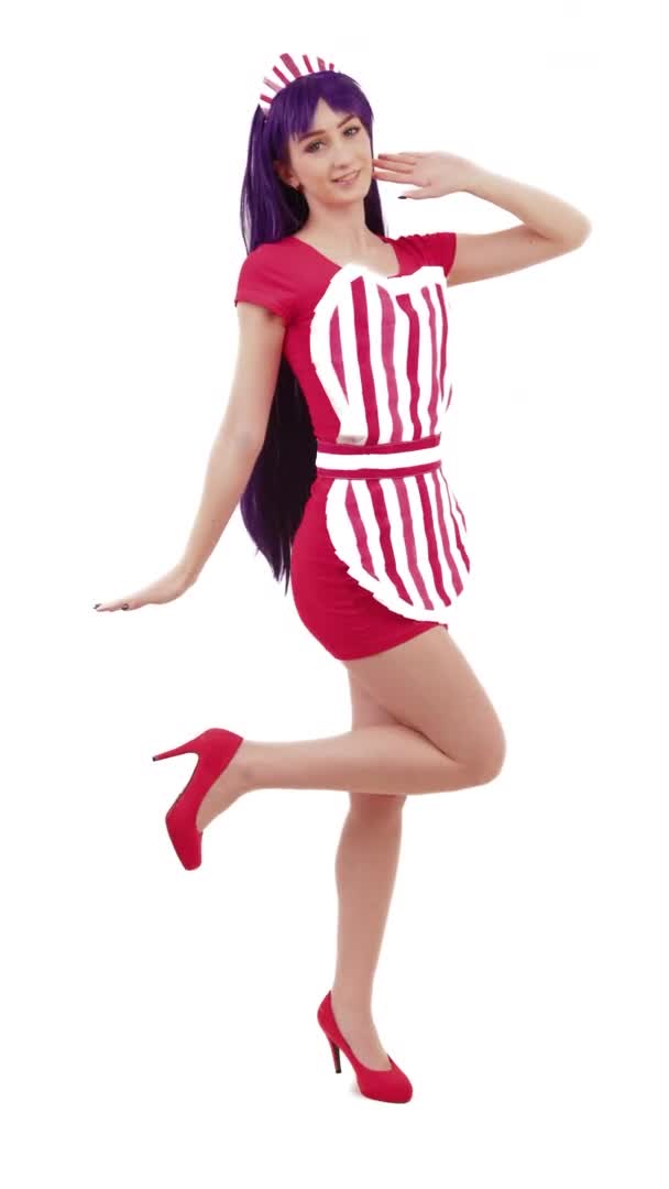 Кокетлива довгошерста жінка в її 20-х позах і піднімає свою довгу ногу в міні-червоній сукні вертикальний студійний знімок — стокове відео