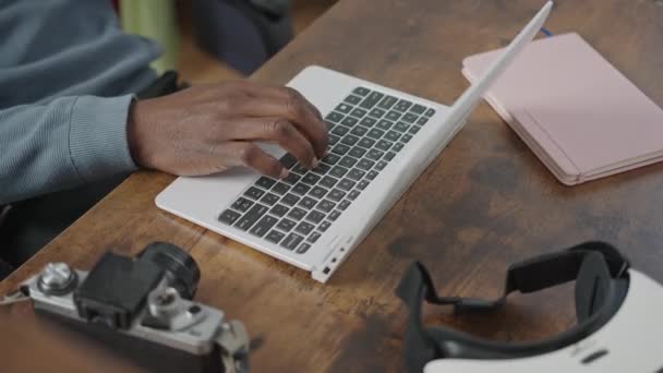 Donker houten bureau man typen op computer laptop toetsenbord met notebook VR-headset en koffiekop — Stockvideo
