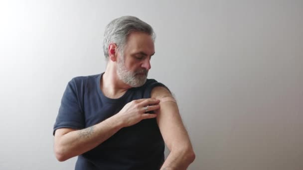 Man van middelbare leeftijd toont de arm patch na vaccinatie - immunisatie concept — Stockvideo
